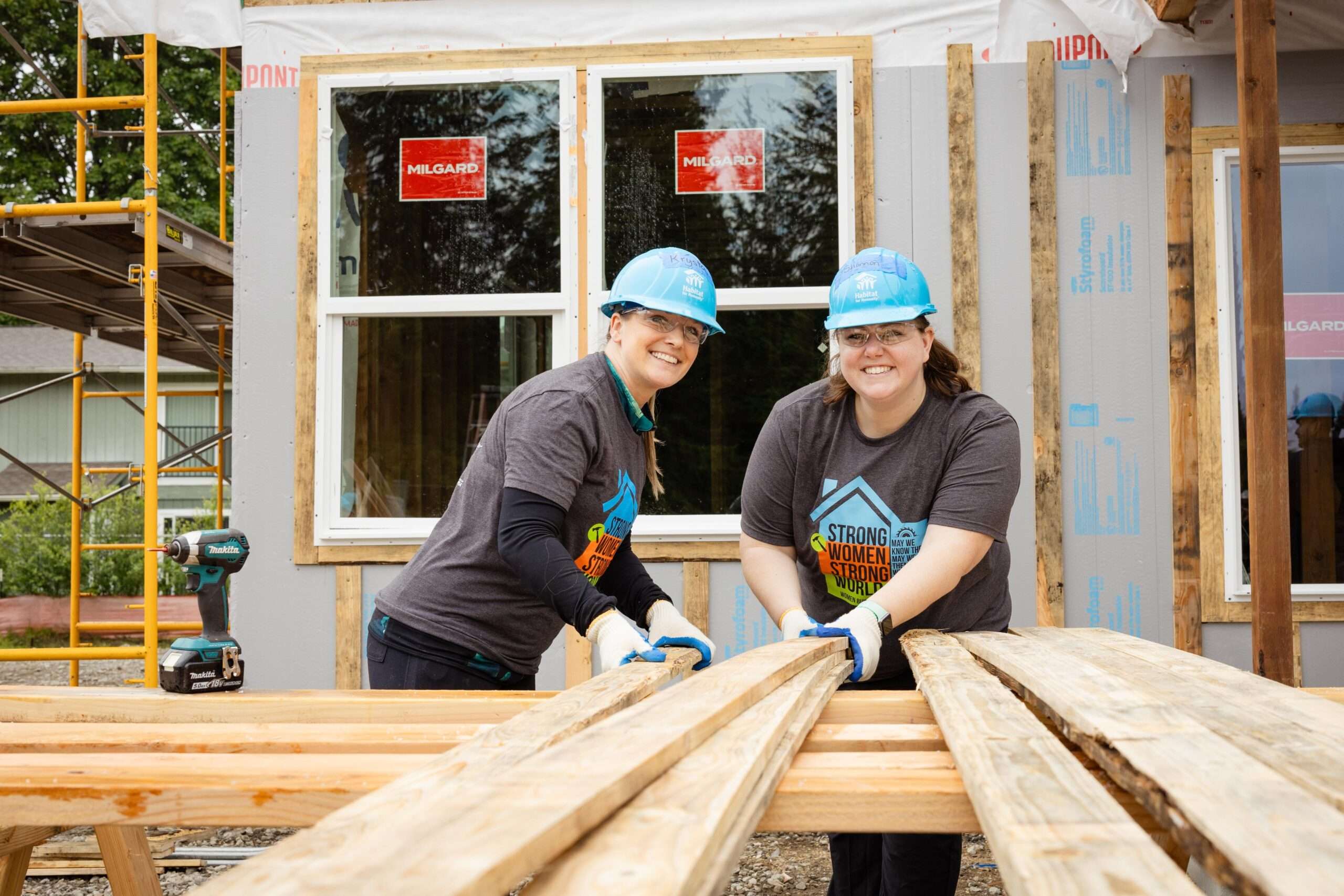 Two women sort lumber on the construction site.