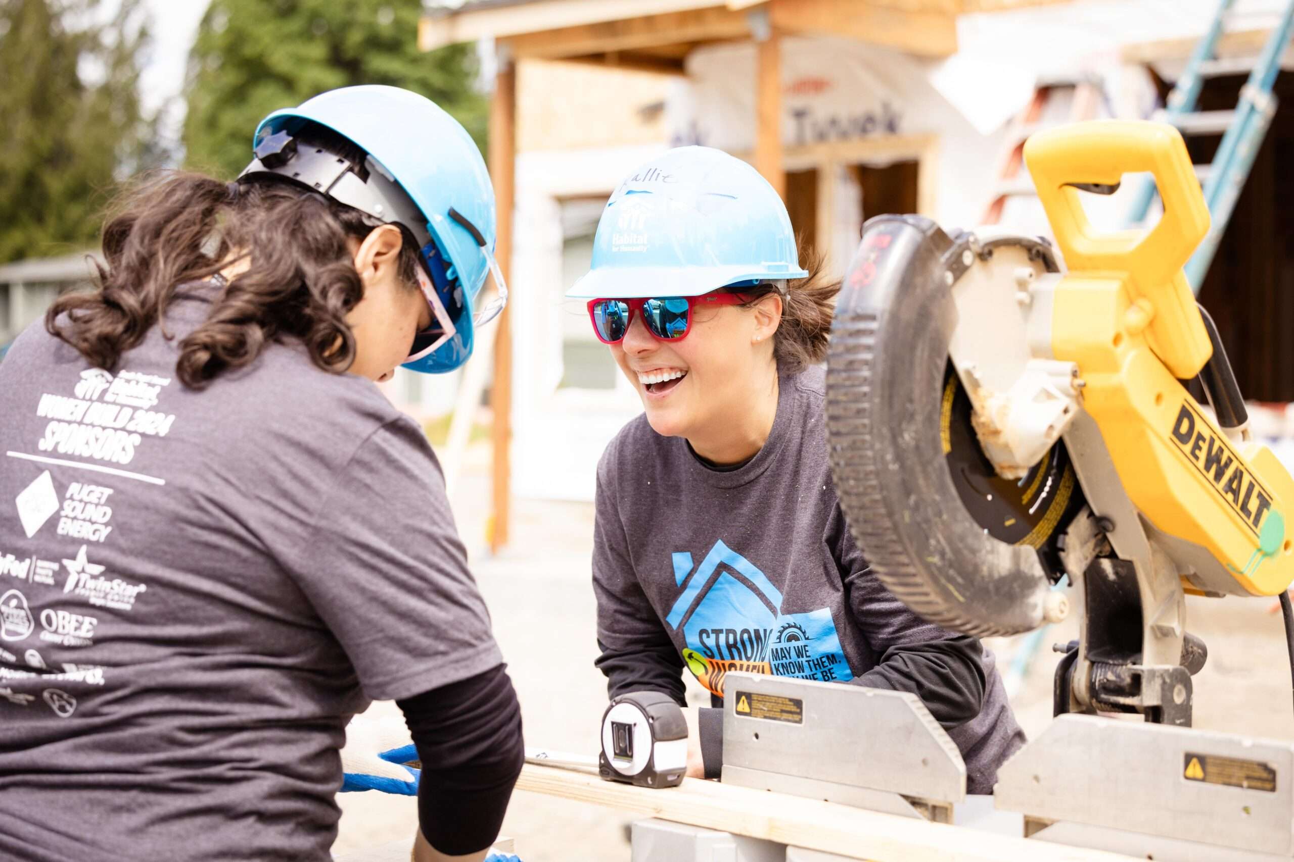 Women working together next to power miter box.