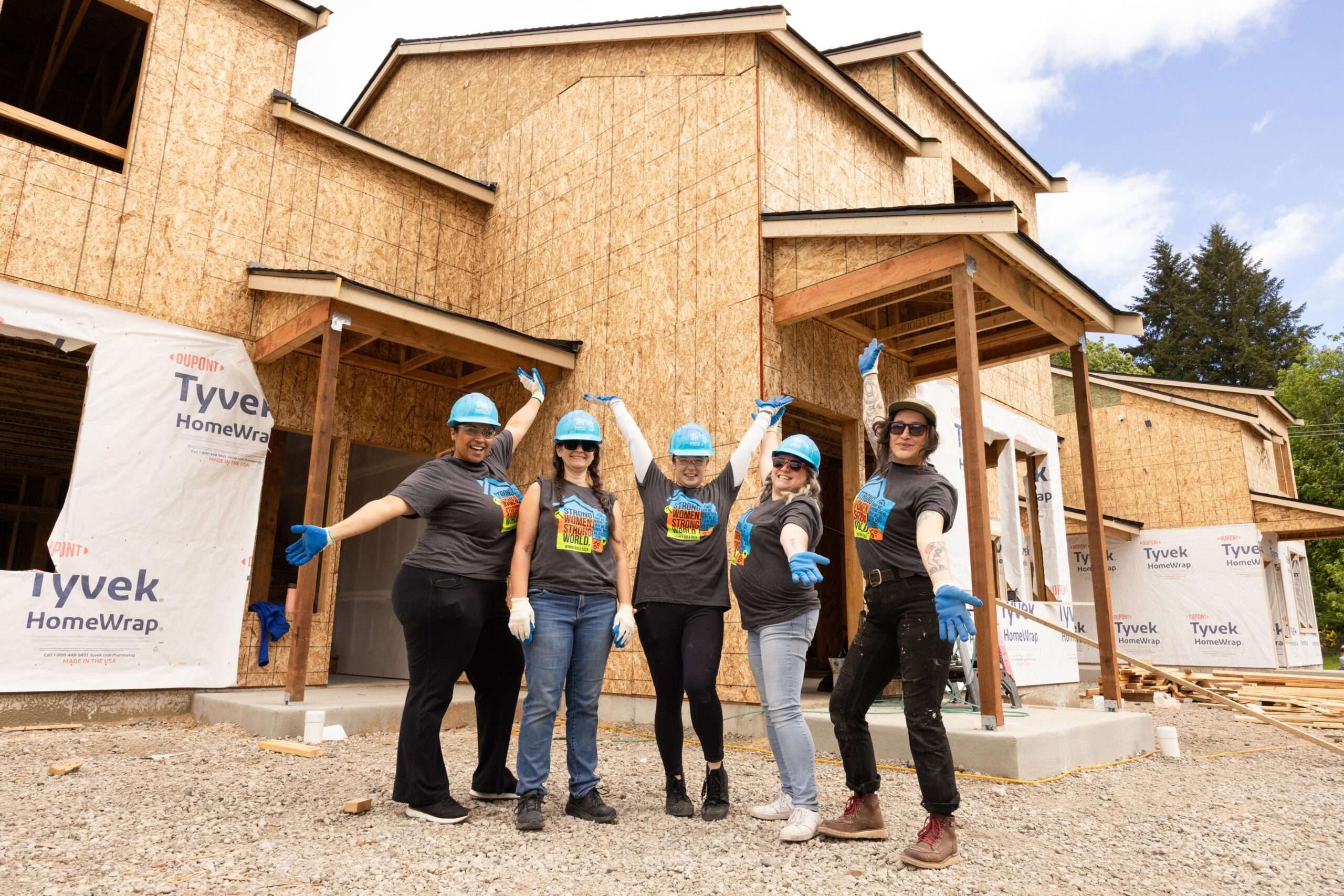 Group of volunteers poses in front of home under construction.