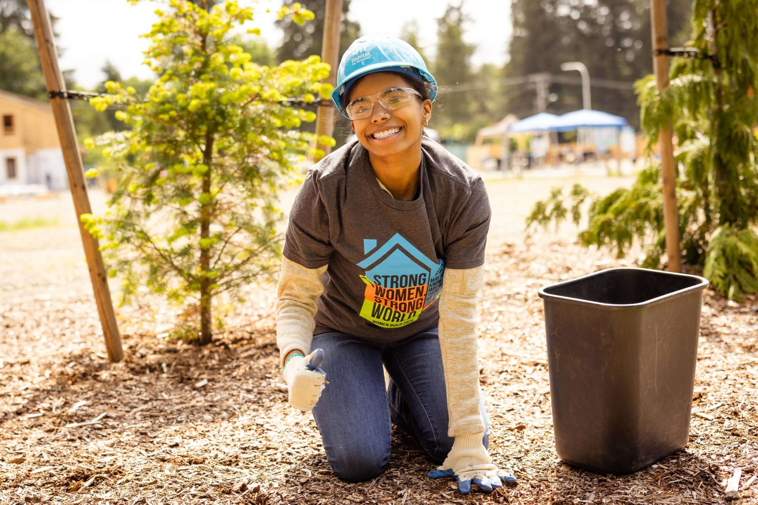 Woman gives thumbs up as she works on landscaping.